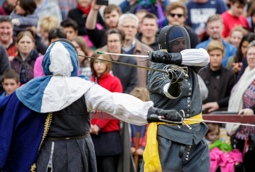 Two rapier fencers fighting at a public demo